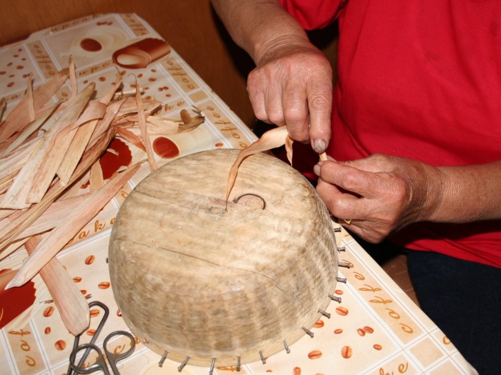 Zobraziť fotografiu Výrobkyňa pri pletení košíka zo stáčaného šúpolia na drevenej forme