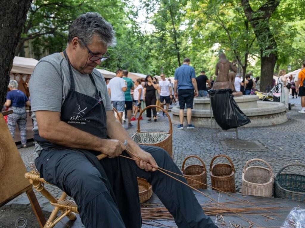 Show photo Výrobca pri predvádzaní remesla - pletení košíka z prútia